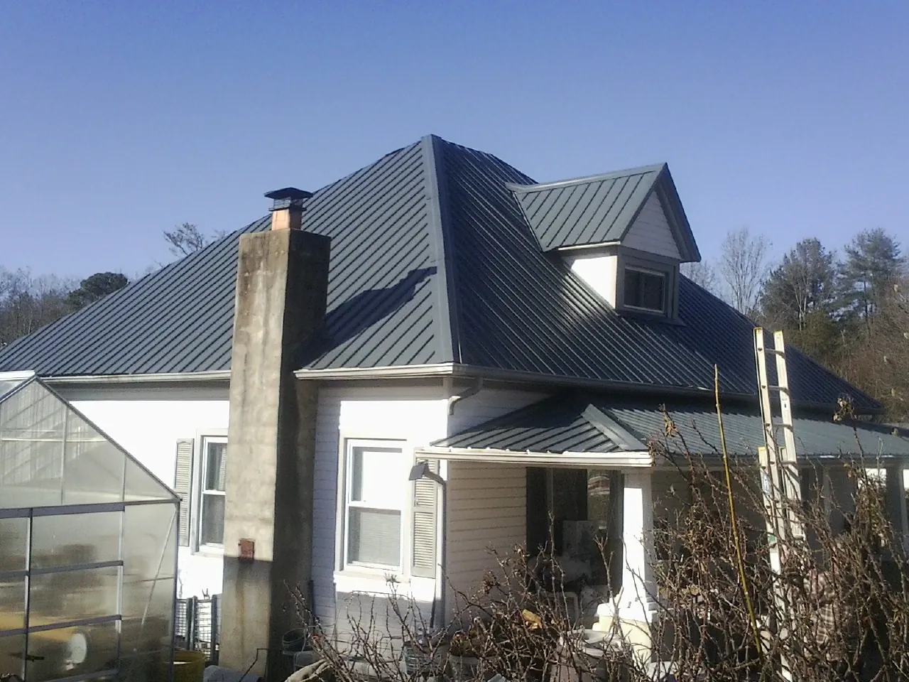 Dark blue standing seam metal roof on a white farmhouse with dormer — Slate & Tile Roof Repair by Roofing Brothers in Fremont Center