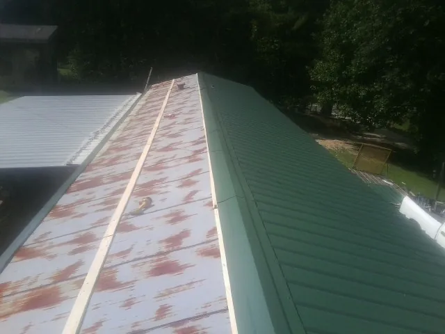 Old rusted panels beside newly installed green metal roofing — Wind Damage Roof Repair by Roofing Brothers in Fremont Center