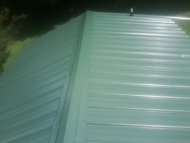 New green metal panels meeting at the ridge of a roof — Flat Roof Repair work by our crew in Fremont Center