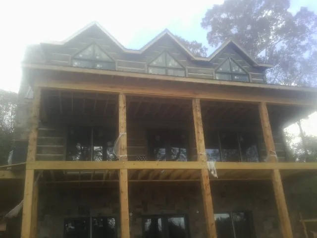 Dormers and porch framing on a large log home under construction — Roof Coating work by our crew in Fremont Center