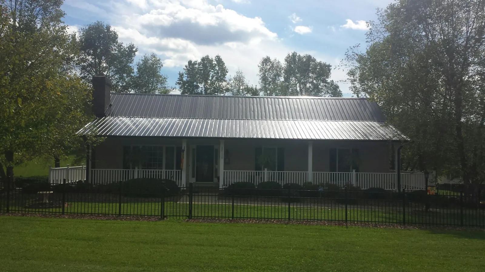 Gray metal roof on a brick ranch with a full width front porch — Gutter Guard Installation work by our crew in Fremont Center