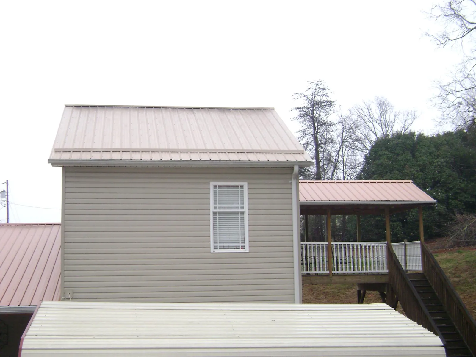 Tan metal roofs on a two story addition and attached porch, from a Roof Replacement job in Fremont Center