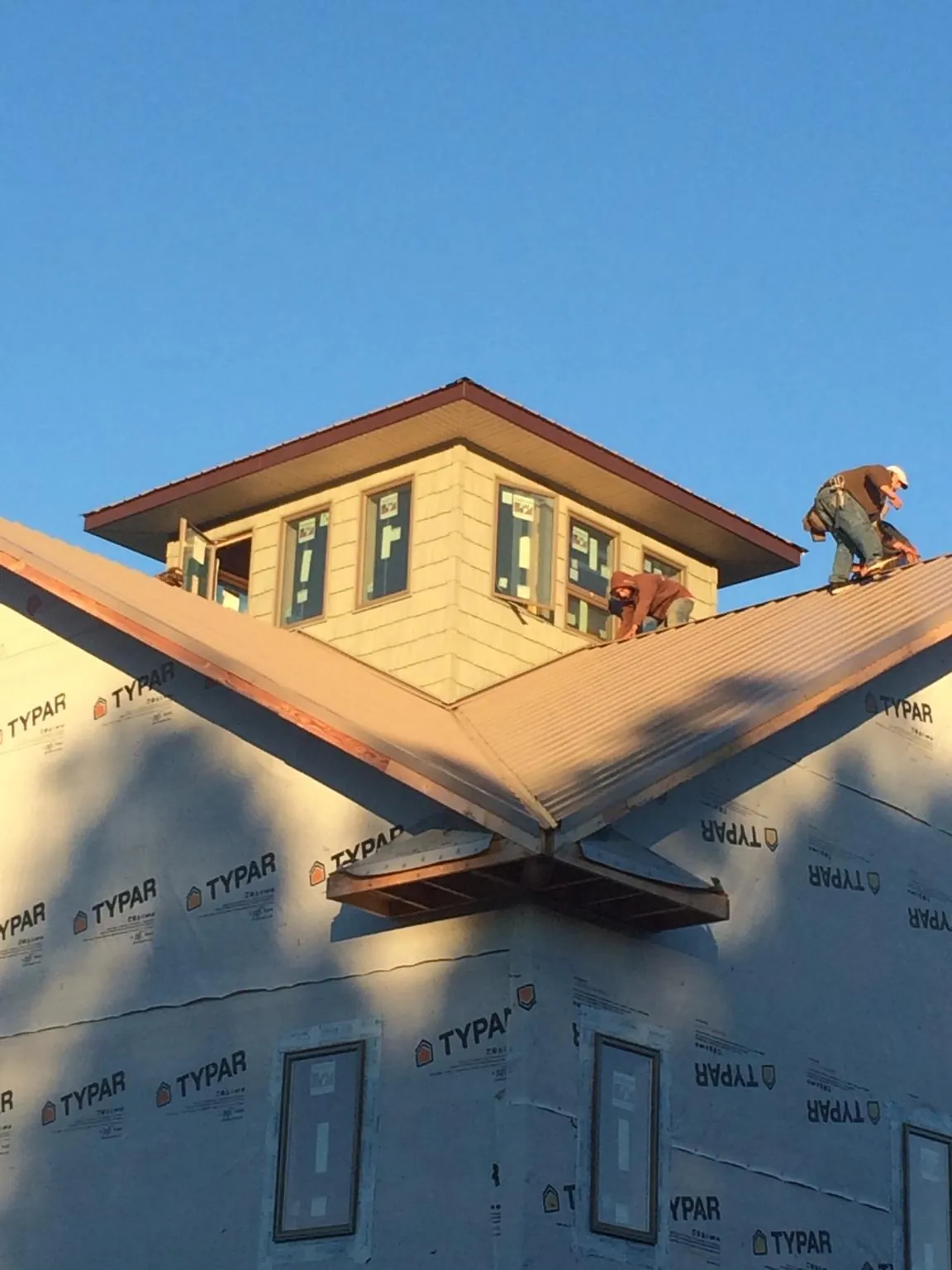 Roofers working around a rooftop cupola on a new metal roof at sunset — Roof Waterproofing in Fremont Center by Roofing Brothers